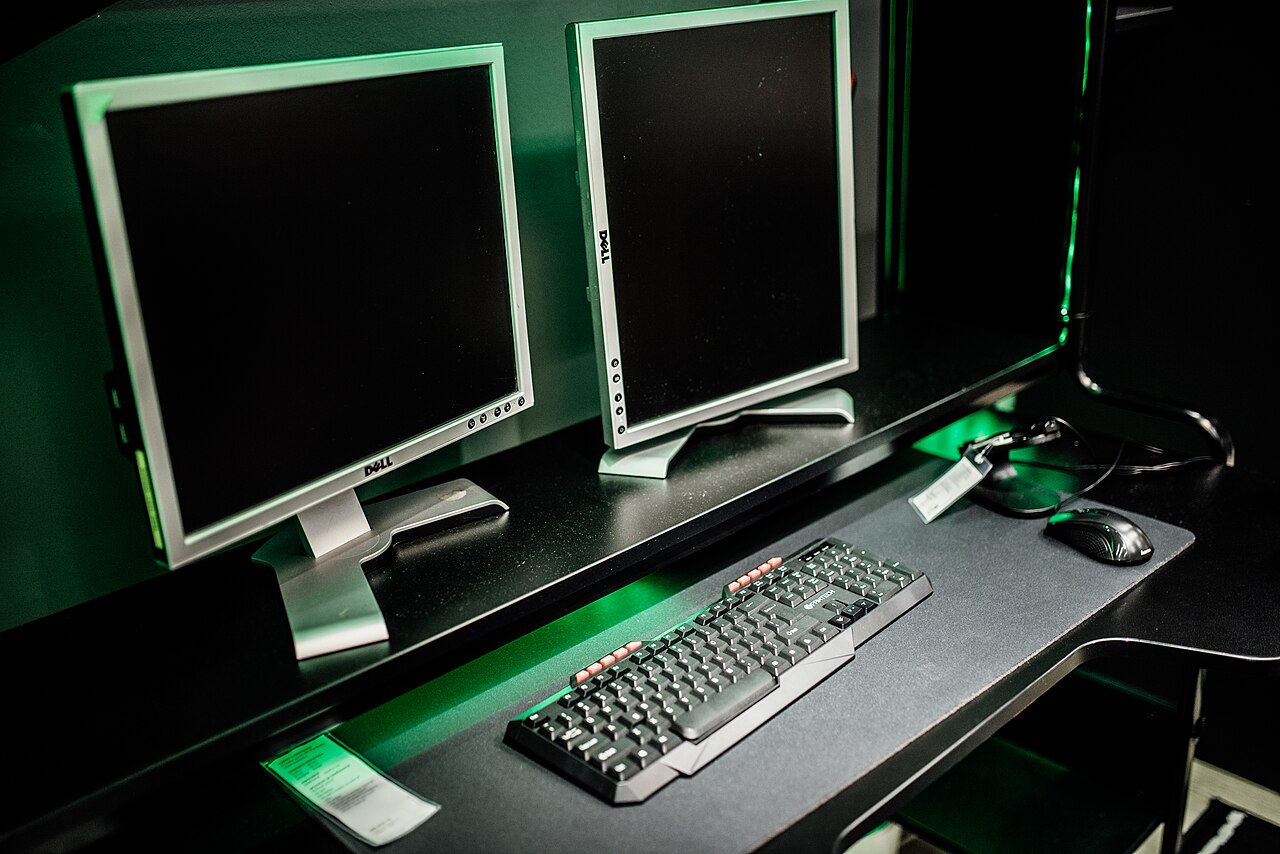 Dual monitor setup in a gaming room with keyboard and mouse in focus.jpg